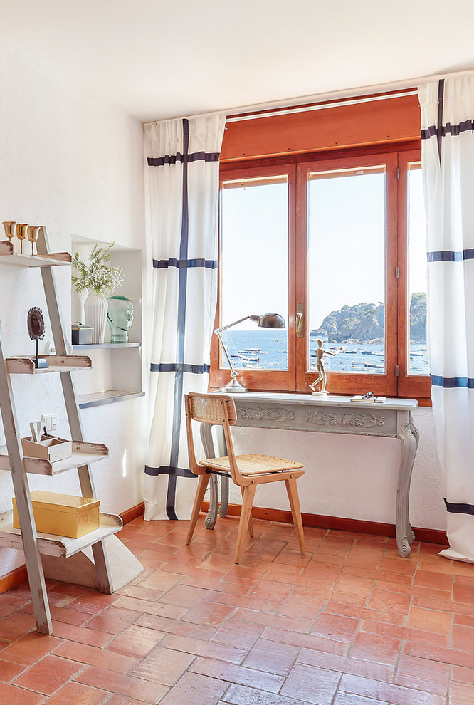 This is an example of a small beach style study room in Other with white walls, terra-cotta floors, no fireplace, a freestanding desk and red floor.