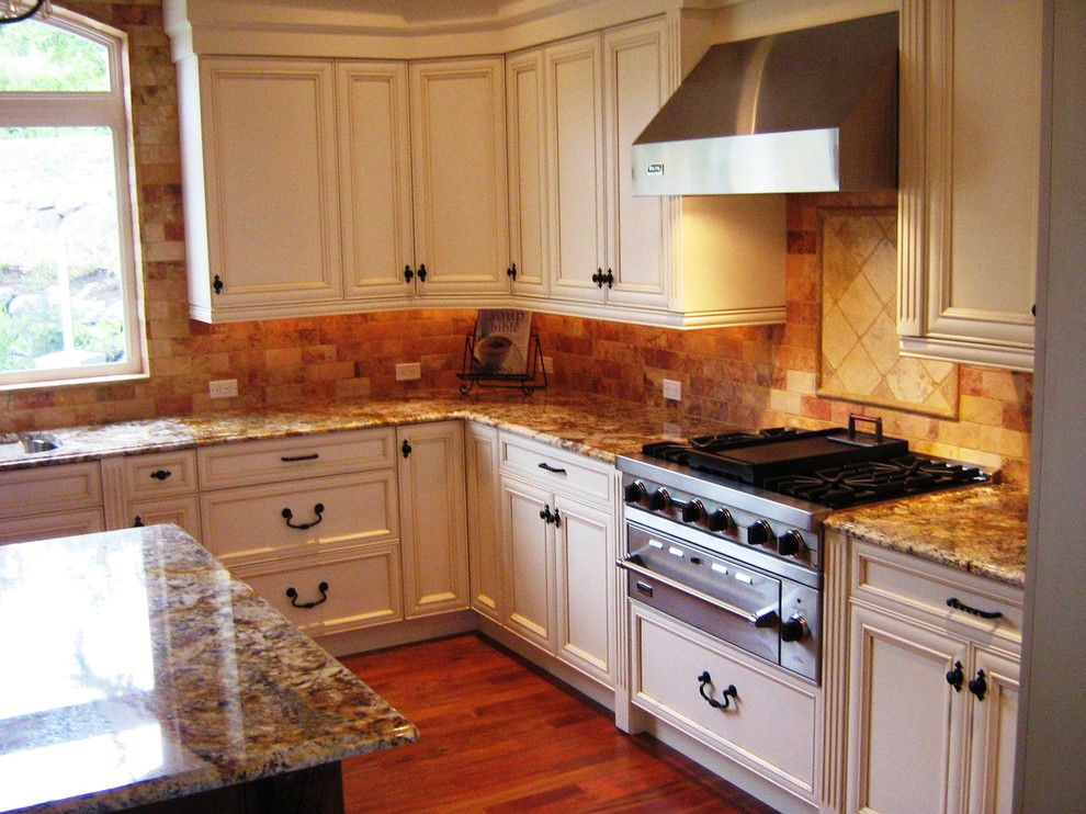This is an example of a traditional kitchen in Seattle with raised-panel cabinets, white cabinets, granite benchtops, brown splashback and stone tile splashback.