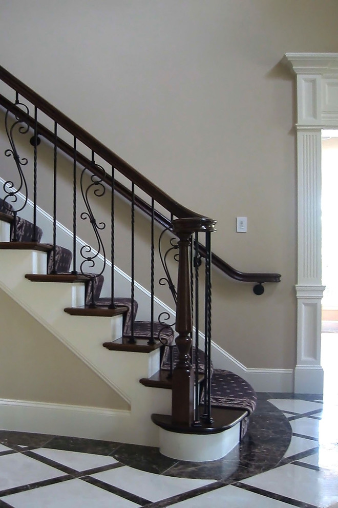 This is an example of a large traditional wood curved staircase in Boston with wood railing and painted wood risers.