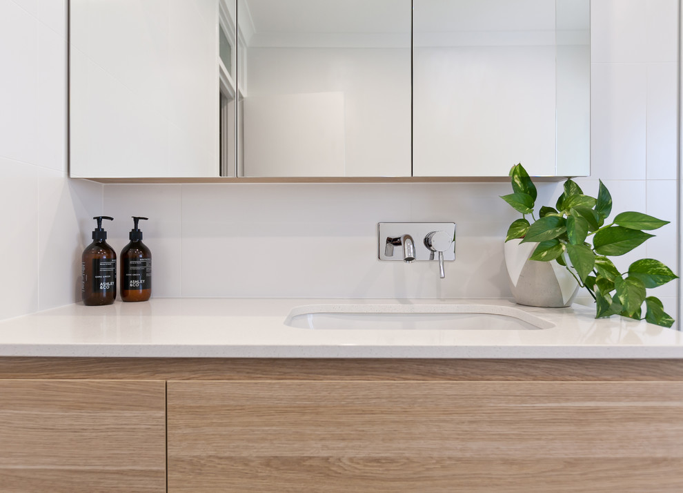 Photo of a small modern kids bathroom in Perth with furniture-like cabinets, light wood cabinets, a freestanding tub, an open shower, white tile, ceramic tile, white walls, porcelain floors, an undermount sink, engineered quartz benchtops, grey floor, an open shower and white benchtops.