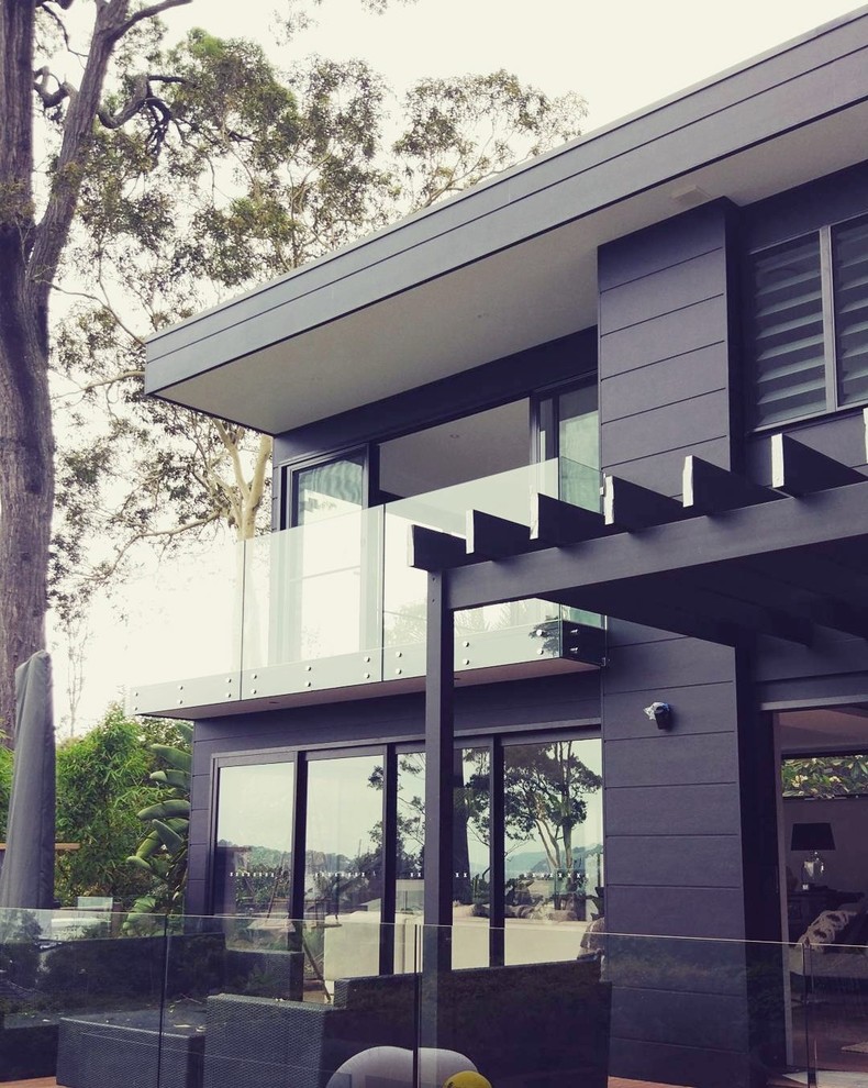 Mid-sized contemporary two-storey black house exterior in Sydney with a flat roof and a metal roof.
