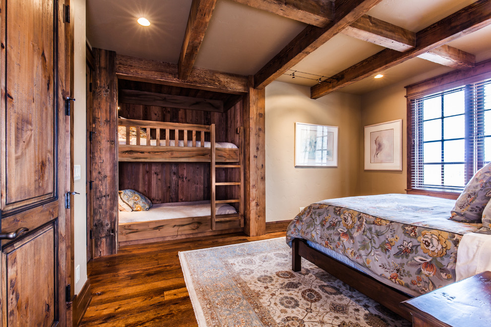 Mid-sized mountain style guest medium tone wood floor bedroom photo with beige walls and no fireplace