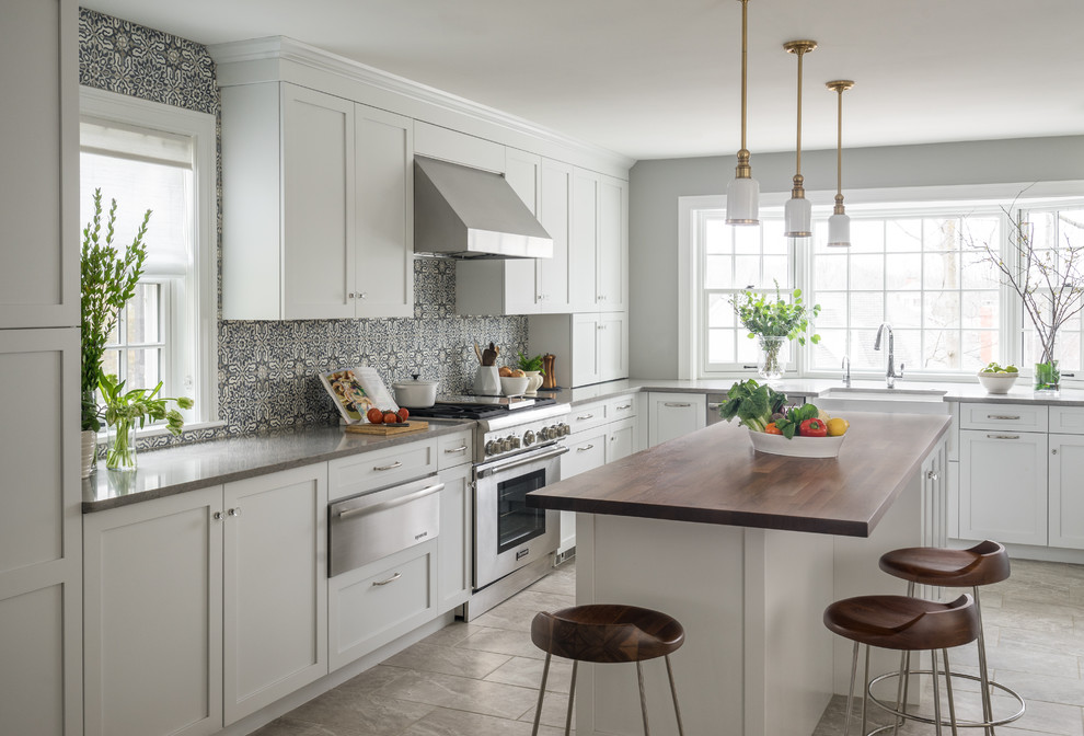 Inspiration for a transitional l-shaped gray floor kitchen remodel in Boston with a farmhouse sink, shaker cabinets, white cabinets, wood countertops, blue backsplash, porcelain backsplash, stainless steel appliances and an island