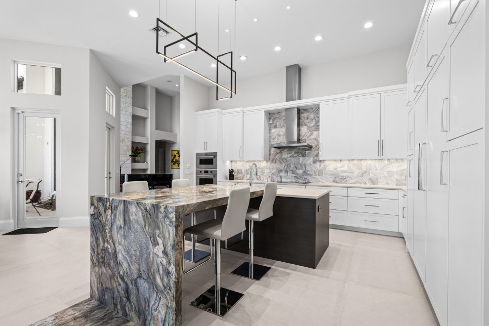 Design ideas for an expansive contemporary grey and white l-shaped open plan kitchen in Miami with a submerged sink, shaker cabinets, white cabinets, quartz worktops, multi-coloured splashback, marble splashback, integrated appliances, porcelain flooring, an island, beige floors and white worktops.