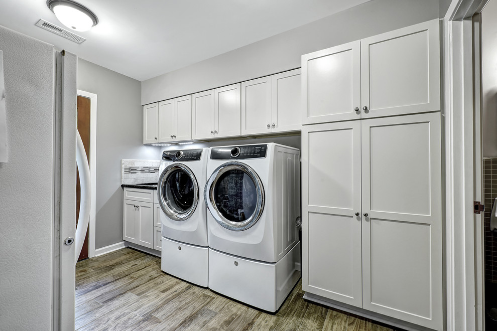 Inspiration for a mid-sized transitional single-wall dedicated laundry room in Charleston with a single-bowl sink, shaker cabinets, white cabinets, granite benchtops, grey walls, porcelain floors, a side-by-side washer and dryer and beige floor.