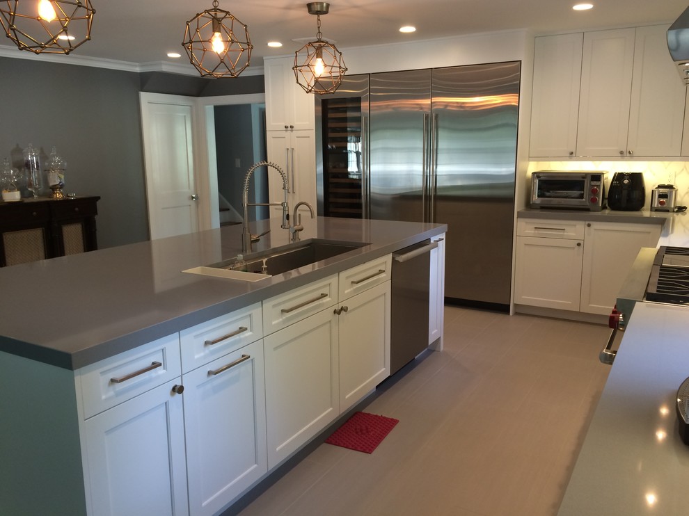Inspiration for a large transitional l-shaped eat-in kitchen in New York with an undermount sink, shaker cabinets, white cabinets, quartz benchtops, white splashback, stone tile splashback, stainless steel appliances, porcelain floors and with island.