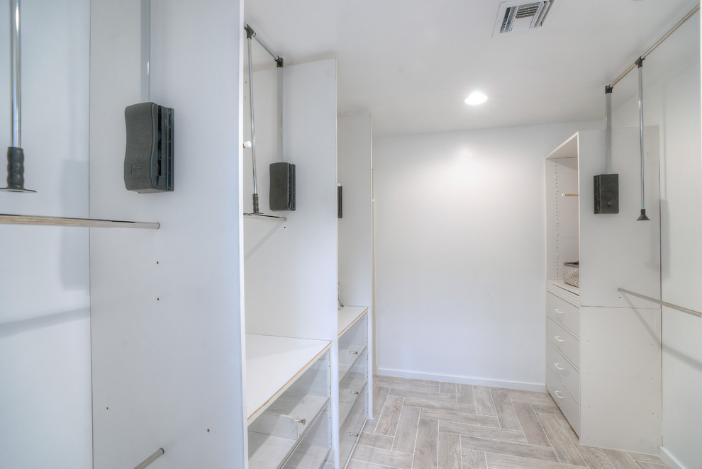 This is an example of a mid-sized arts and crafts gender-neutral walk-in wardrobe with white cabinets.