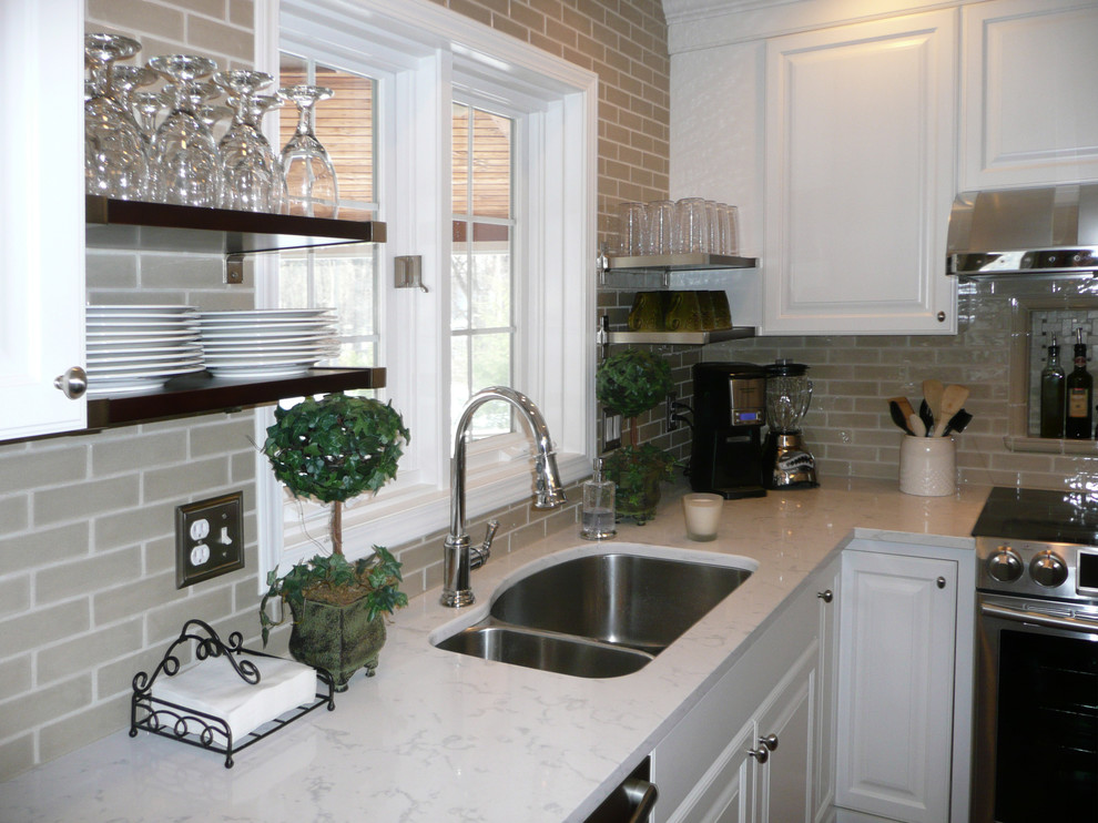 Mid-sized transitional l-shaped medium tone wood floor and brown floor eat-in kitchen photo with an undermount sink, raised-panel cabinets, white cabinets, quartz countertops, subway tile backsplash, stainless steel appliances, an island, beige backsplash and white countertops