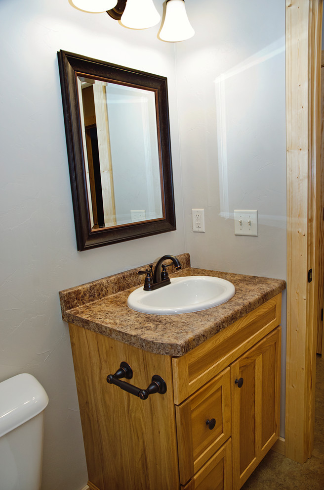 Mid-sized mountain style master beige tile linoleum floor and brown floor drop-in bathtub photo with recessed-panel cabinets, light wood cabinets, a two-piece toilet, beige walls, a drop-in sink and laminate countertops