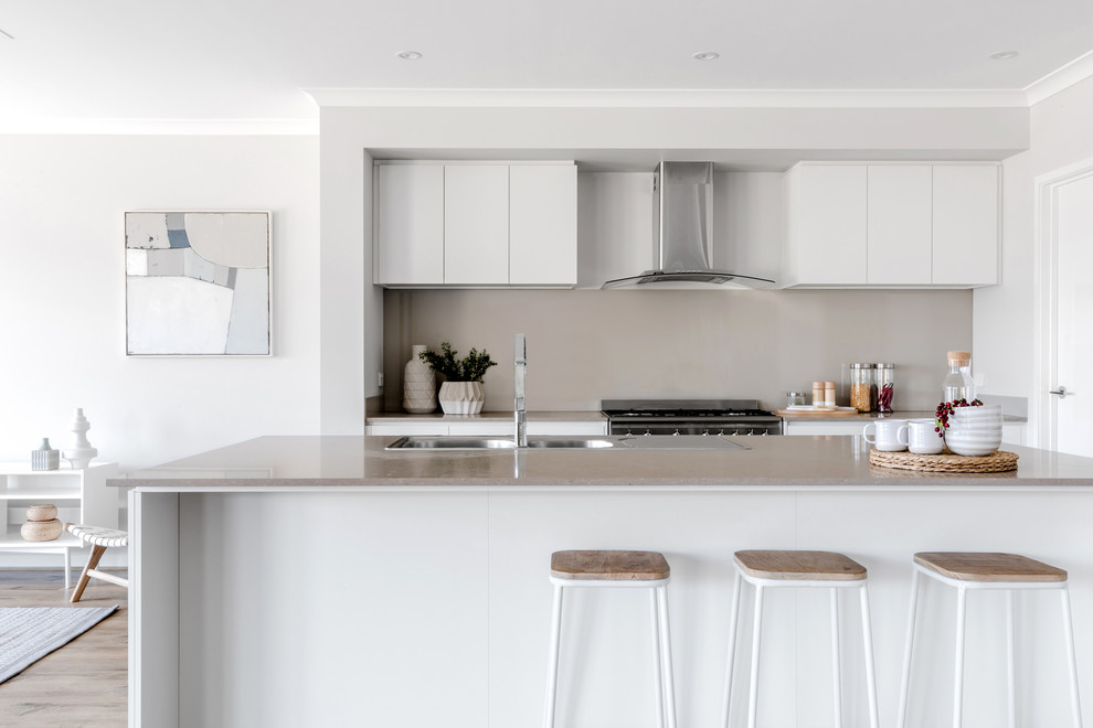 Photo of a contemporary galley open plan kitchen in Melbourne with flat-panel cabinets, white cabinets, with island and grey benchtop.
