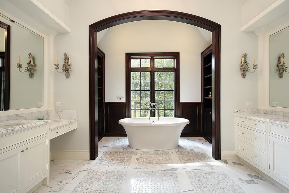 Large transitional master marble floor and gray floor freestanding bathtub photo in Toronto with recessed-panel cabinets, white cabinets, gray walls, an undermount sink and marble countertops