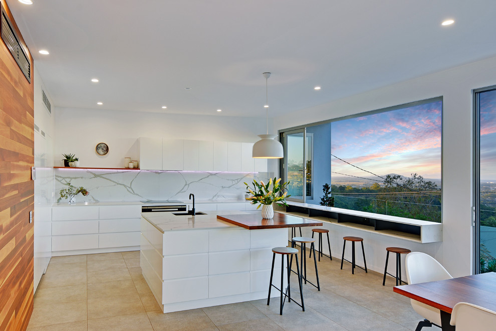 Design ideas for a large contemporary l-shaped open plan kitchen in Sunshine Coast with with island, flat-panel cabinets, white cabinets, white splashback, white benchtop, marble benchtops, marble splashback, stainless steel appliances, a single-bowl sink, porcelain floors and grey floor.