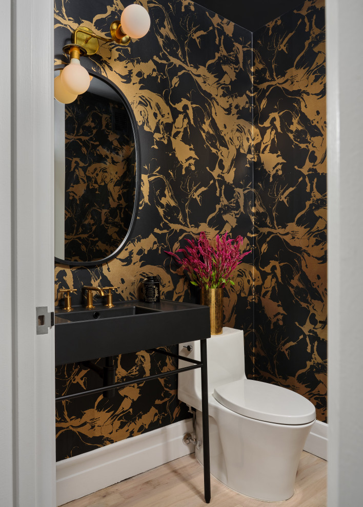 Powder room - contemporary light wood floor, beige floor and wallpaper powder room idea in New York with multicolored walls and a console sink