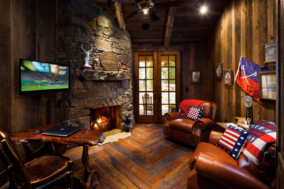Photo of a small country study room in Other with dark hardwood floors, a standard fireplace, a stone fireplace surround and a freestanding desk.