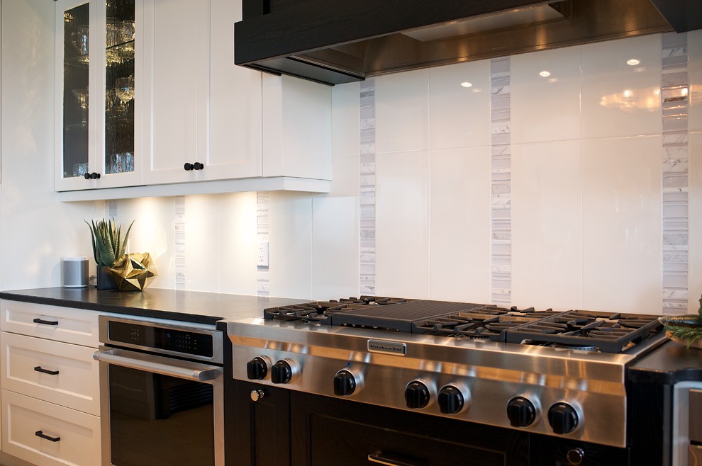 Inspiration for a large transitional u-shaped light wood floor eat-in kitchen remodel in Edmonton with shaker cabinets, white cabinets, granite countertops, white backsplash, stone tile backsplash, stainless steel appliances and an island
