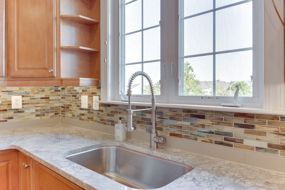 Mid-sized transitional u-shaped medium tone wood floor kitchen photo in Baltimore with an undermount sink, raised-panel cabinets, medium tone wood cabinets, granite countertops, glass sheet backsplash, stainless steel appliances and an island