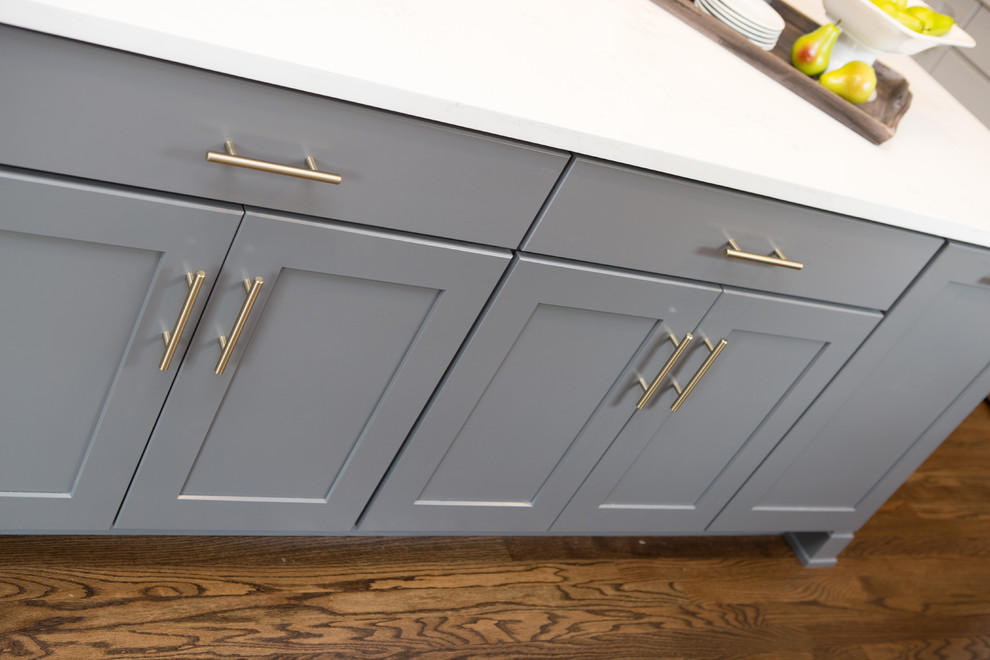 Eat-in kitchen - mid-sized transitional u-shaped medium tone wood floor and brown floor eat-in kitchen idea in Chicago with a farmhouse sink, shaker cabinets, quartz countertops, white backsplash, subway tile backsplash, stainless steel appliances, an island and white countertops