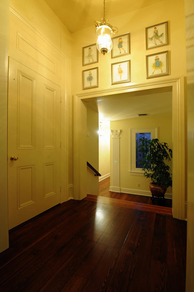 Large traditional hallway in New Orleans with white walls and porcelain floors.