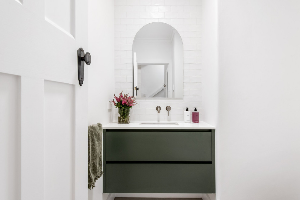 Свежая идея для дизайна: маленькая ванная комната в современном стиле с плоскими фасадами, зелеными фасадами, унитазом-моноблоком, белой плиткой, плиткой кабанчик, белыми стенами, полом из керамической плитки, врезной раковиной, столешницей из известняка, серым полом, белой столешницей, тумбой под одну раковину и подвесной тумбой для на участке и в саду - отличное фото интерьера