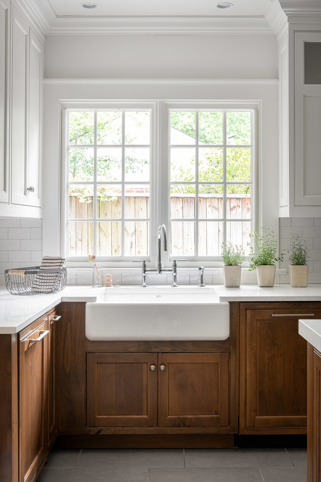 Inspiration for a large beach style u-shaped eat-in kitchen in Atlanta with a farmhouse sink, shaker cabinets, white cabinets, quartz benchtops, white splashback, subway tile splashback, panelled appliances, ceramic floors, with island, grey floor and white benchtop.