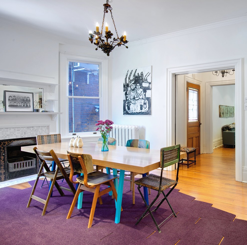 Photo of a large eclectic separate dining room in Toronto with white walls, medium hardwood floors, a standard fireplace and a tile fireplace surround.