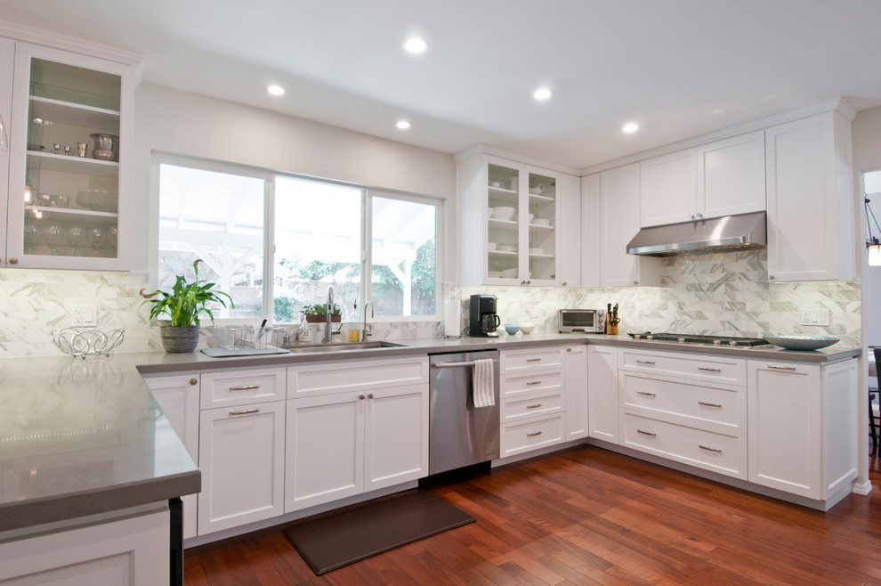 Design ideas for a mid-sized transitional u-shaped separate kitchen in Los Angeles with an undermount sink, shaker cabinets, white cabinets, quartzite benchtops, white splashback, marble splashback, stainless steel appliances, light hardwood floors, a peninsula, brown floor and grey benchtop.