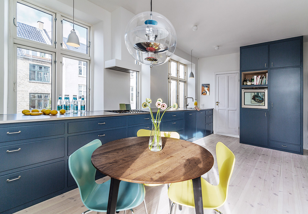 Inspiration for a scandinavian single-wall eat-in kitchen in Copenhagen with flat-panel cabinets, blue cabinets, white splashback, coloured appliances, light hardwood floors and no island.