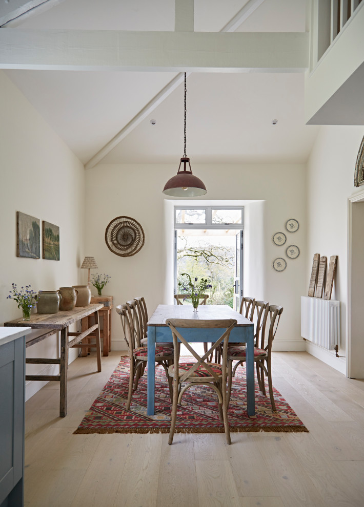 Inspiration for a medium sized eclectic dining room in Devon with banquette seating, white walls, medium hardwood flooring, brown floors, exposed beams and feature lighting.
