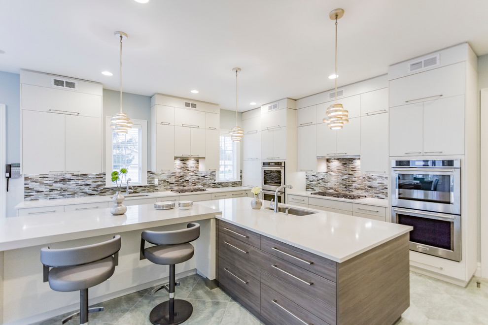 This is an example of a large contemporary l-shaped eat-in kitchen in New York with an undermount sink, flat-panel cabinets, white cabinets, quartz benchtops, multi-coloured splashback, glass tile splashback, panelled appliances, ceramic floors and multiple islands.