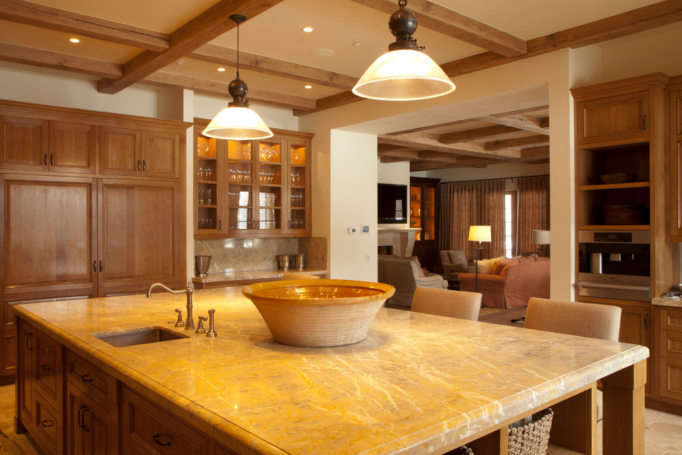 Example of a limestone floor enclosed kitchen design with paneled appliances and an island