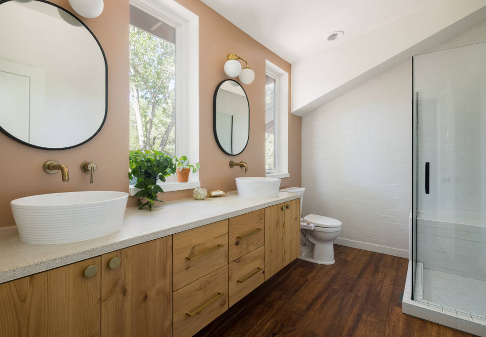 Idées déco pour une salle de bain principale éclectique en bois clair de taille moyenne avec un placard à porte plane, une douche d'angle, un carrelage beige, des carreaux de céramique, un mur beige, un sol en bois brun, une vasque, un plan de toilette en surface solide, une cabine de douche à porte battante, un plan de toilette blanc, meuble double vasque, meuble-lavabo suspendu et un plafond voûté.