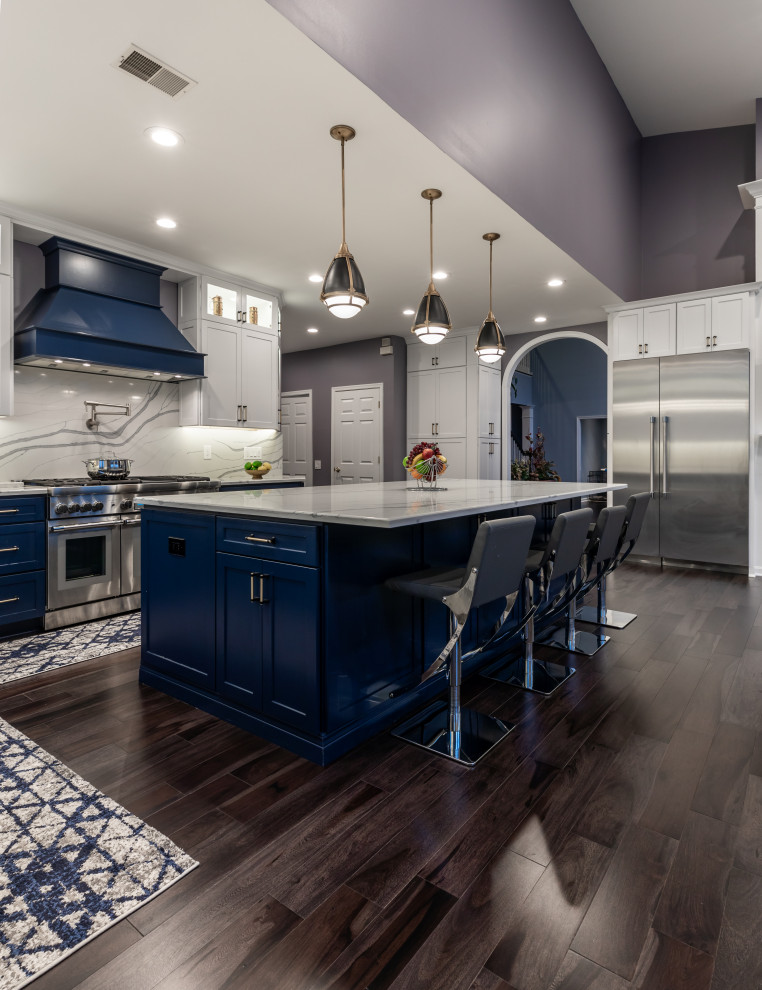 Inspiration for a mid-sized contemporary l-shaped eat-in kitchen in DC Metro with recessed-panel cabinets, blue cabinets, marble benchtops, white splashback, stainless steel appliances, medium hardwood floors, with island, grey floor and white benchtop.