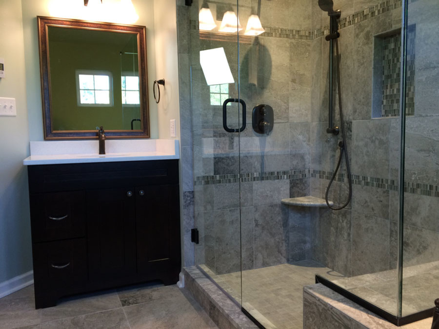 Design ideas for a mid-sized transitional master bathroom in Other with gray tile, porcelain tile, porcelain floors, engineered quartz benchtops, flat-panel cabinets, dark wood cabinets, a drop-in tub, a corner shower, grey walls, an undermount sink, grey floor, a hinged shower door and white benchtops.