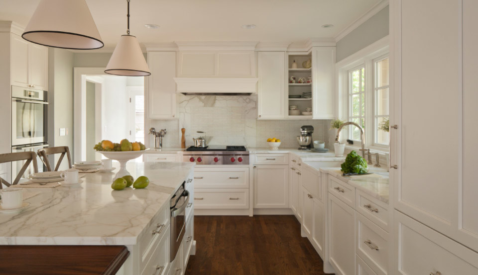 Inspiration for a mid-sized transitional l-shaped medium tone wood floor enclosed kitchen remodel in Toronto with a farmhouse sink, recessed-panel cabinets, white cabinets, quartz countertops, white backsplash, stainless steel appliances and an island