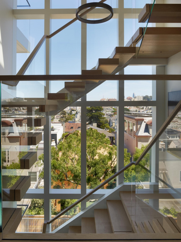 Photo of an expansive modern wood floating staircase in San Francisco with open risers and glass railing.
