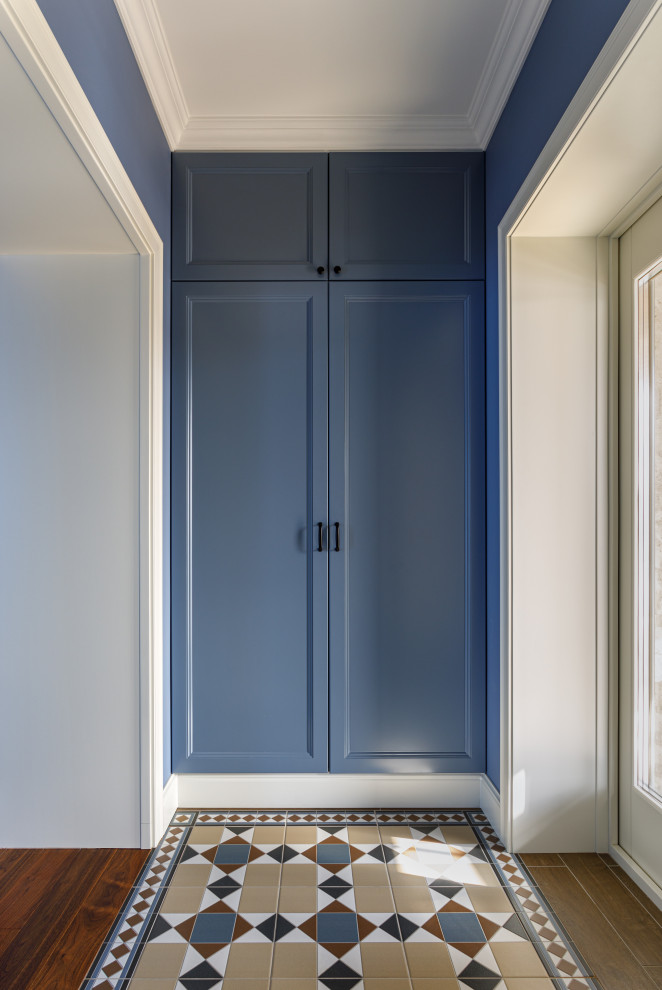 Пример оригинального дизайна: входная дверь среднего размера со шкафом для обуви в современном стиле с синими стенами, полом из керамической плитки, двустворчатой входной дверью, белой входной дверью, оранжевым полом и панелями на стенах