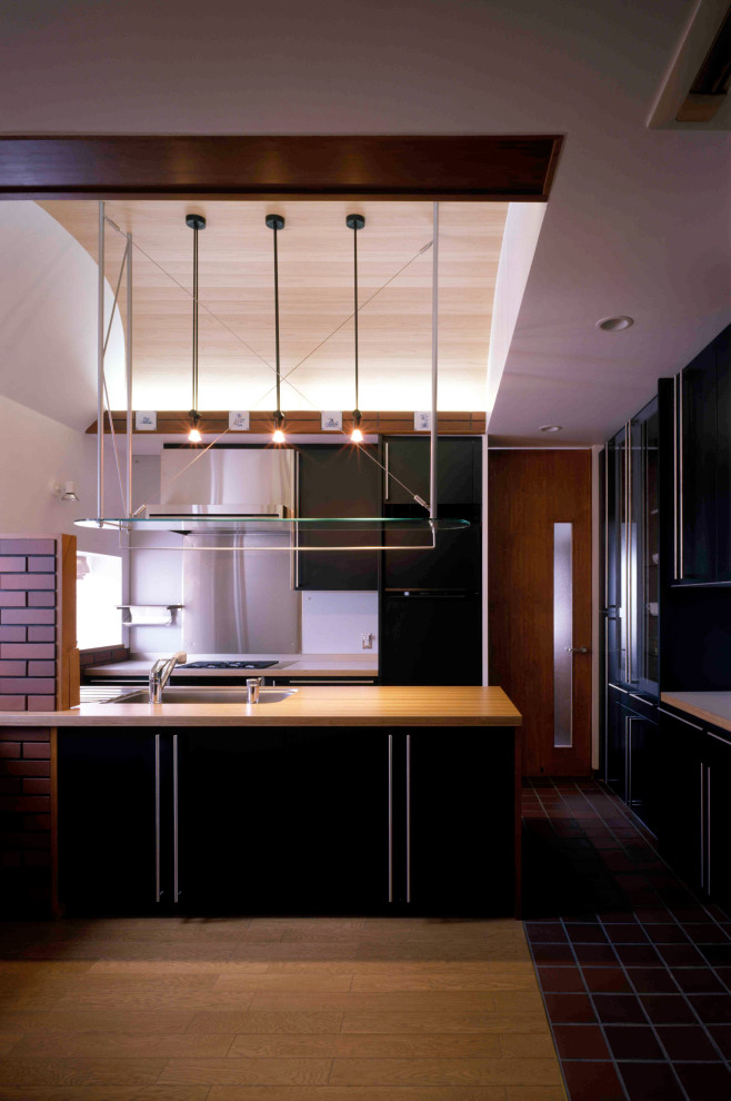 Modern inredning av ett litet brun brunt kök, med en undermonterad diskho, luckor med profilerade fronter, gröna skåp, träbänkskiva, stänkskydd med metallisk yta, rostfria vitvaror, mellanmörkt trägolv, en köksö och brunt golv