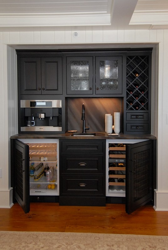 This is an example of a small traditional single-wall wet bar in Orlando with an undermount sink, recessed-panel cabinets, black cabinets, laminate benchtops, multi-coloured splashback and medium hardwood floors.