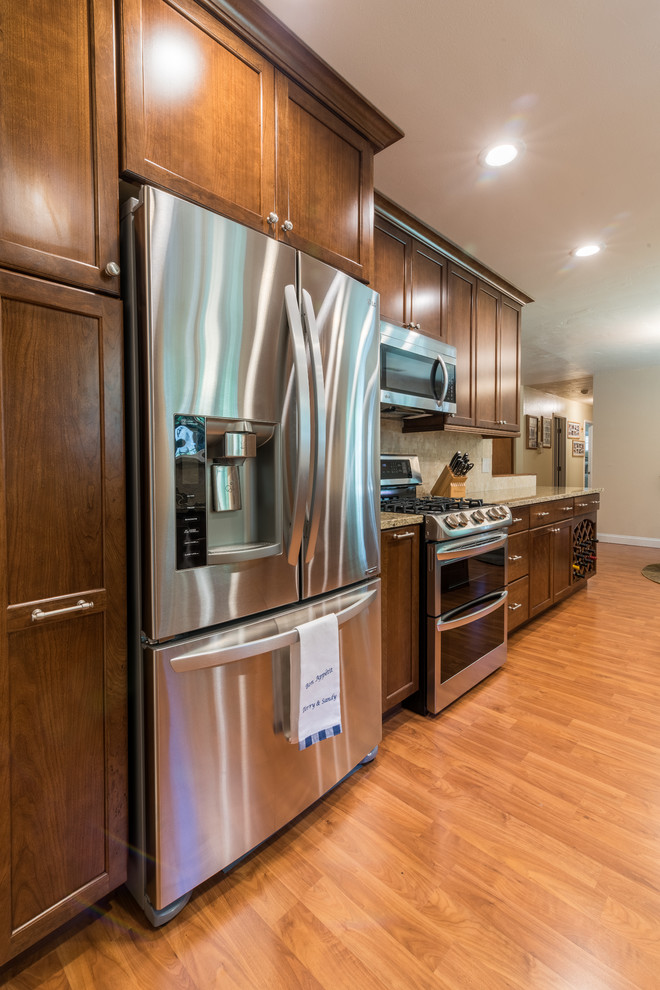 Mid-sized contemporary galley eat-in kitchen in Sacramento with an undermount sink, recessed-panel cabinets, medium wood cabinets, marble benchtops, beige splashback, ceramic splashback, stainless steel appliances, light hardwood floors and no island.