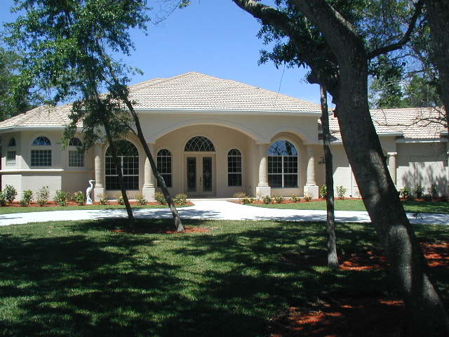 This is an example of a large contemporary one-storey stucco yellow house exterior in Orlando with a hip roof and a tile roof.