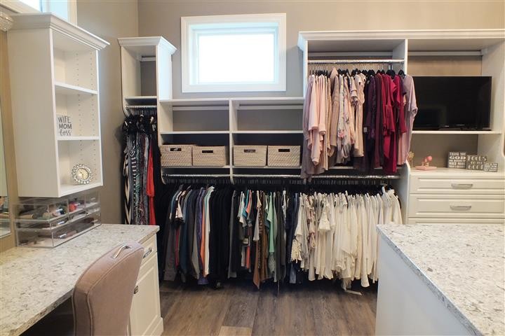 Expansive contemporary gender-neutral walk-in wardrobe in Cleveland with raised-panel cabinets, white cabinets, vinyl floors and brown floor.