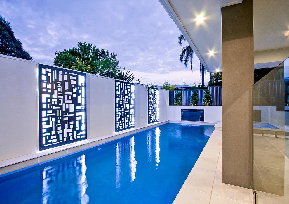 This is an example of a small modern courtyard custom-shaped lap pool in Brisbane with a water feature and natural stone pavers.