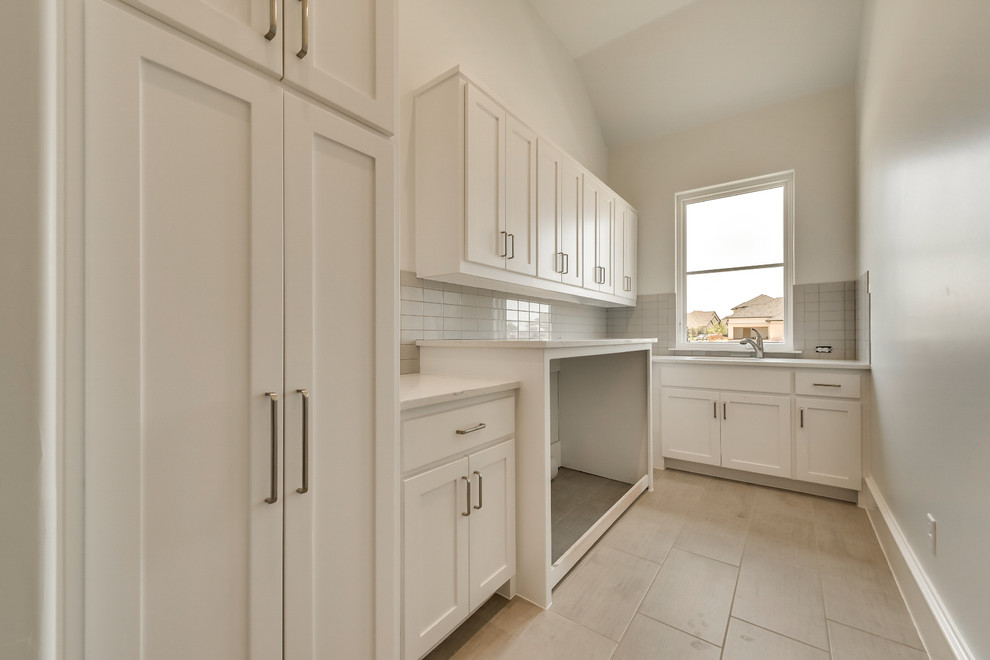 Photo of a mid-sized mediterranean galley dedicated laundry room in Dallas with shaker cabinets, white cabinets, quartz benchtops, beige benchtop, an utility sink, beige walls, ceramic floors, a side-by-side washer and dryer and beige floor.