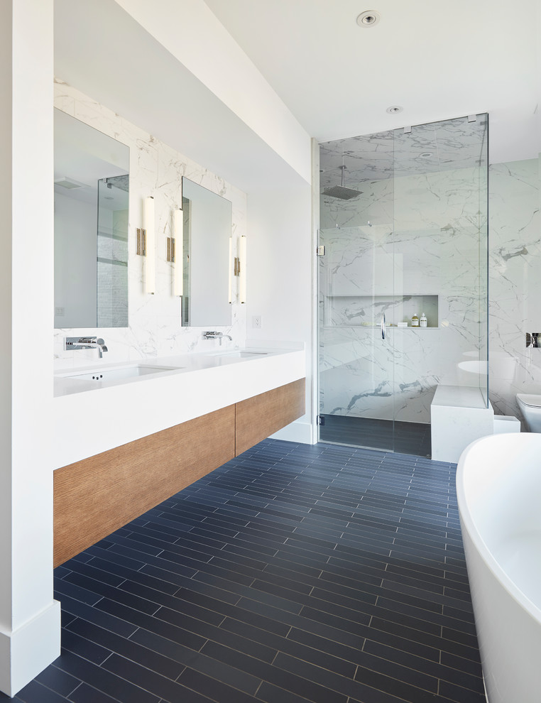 Inspiration for a large contemporary master bathroom in Toronto with flat-panel cabinets, a freestanding tub, a curbless shower, white tile, white walls, ceramic floors, an undermount sink, engineered quartz benchtops, grey floor, a hinged shower door, white benchtops, medium wood cabinets and a wall-mount toilet.