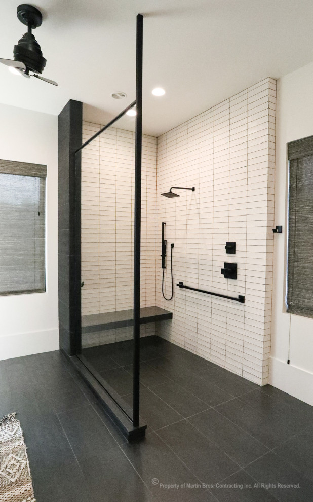 Expansive urban ensuite bathroom in Other with flat-panel cabinets, light wood cabinets, a walk-in shower, a wall mounted toilet, white tiles, ceramic tiles, white walls, porcelain flooring, a submerged sink, engineered stone worktops, black floors, an open shower, black worktops, a shower bench, double sinks and a freestanding vanity unit.