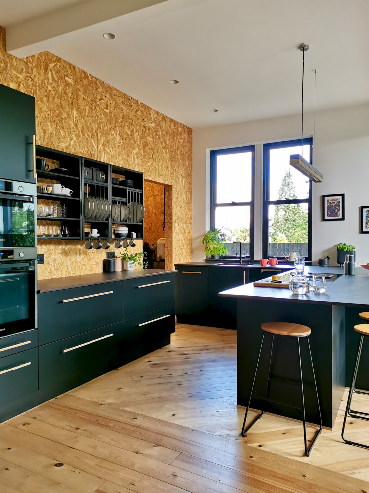 Foto di una cucina scandinava di medie dimensioni con lavello a doppia vasca, ante lisce, ante nere, top in quarzite, elettrodomestici da incasso, parquet chiaro e top nero