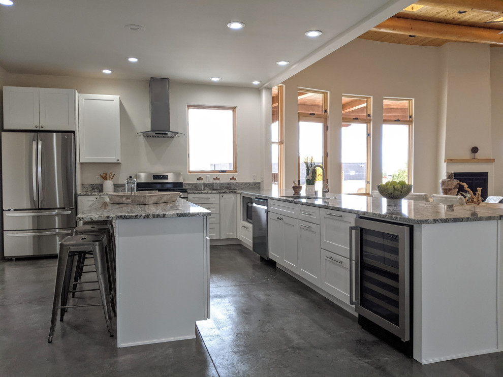 Amerikansk inredning av ett mellanstort grå grått kök, med en enkel diskho, vita skåp, granitbänkskiva, rostfria vitvaror, betonggolv, en köksö och grått golv