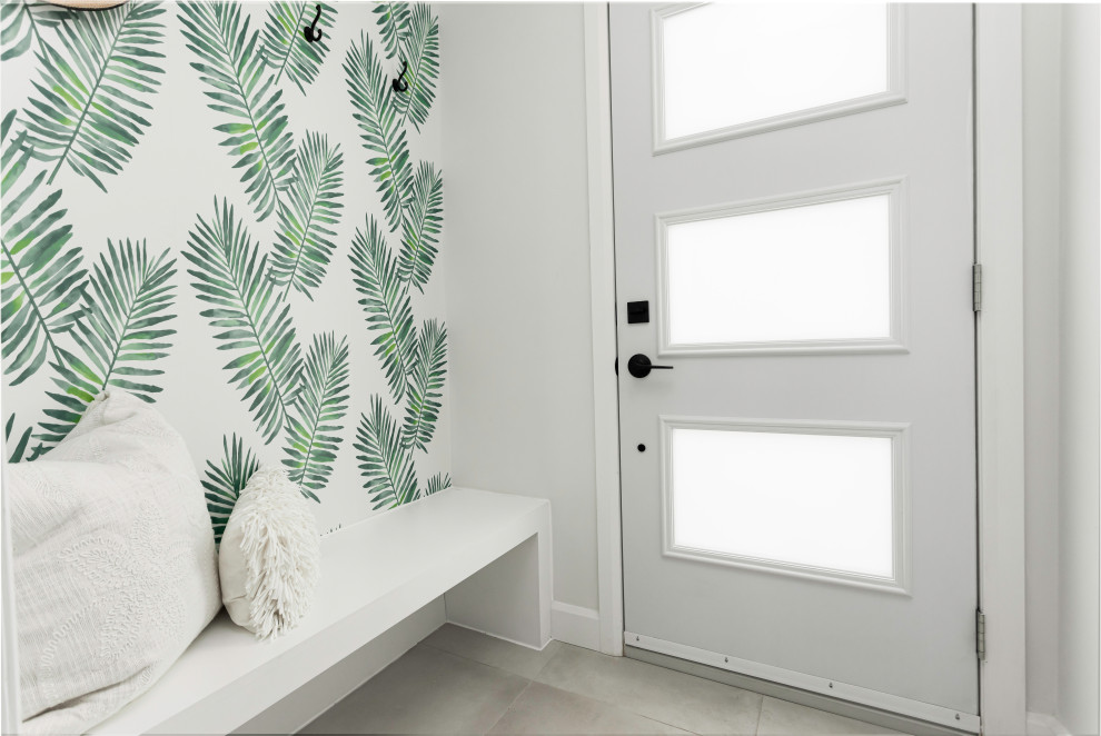 This is an example of a small country foyer in Montreal with green walls, porcelain floors, a single front door, a white front door, grey floor and wallpaper.