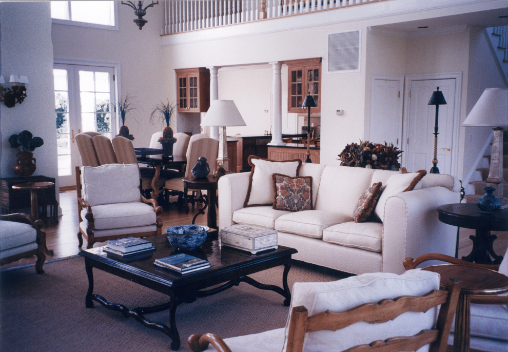 Cette image montre un grand salon traditionnel ouvert avec un mur blanc, un sol en bois brun, aucune cheminée, aucun téléviseur, un sol beige et un plafond voûté.