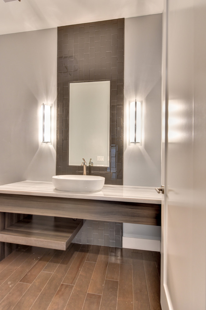 Mid-sized contemporary powder room in Sacramento with open cabinets, light wood cabinets, brown tile, glass tile, beige walls, dark hardwood floors, a vessel sink, quartzite benchtops, brown floor and white benchtops.